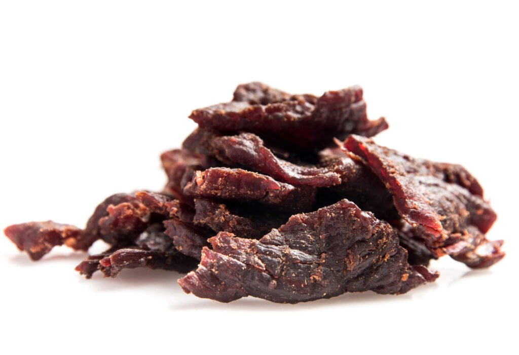Various types of beef jerky and dried meats for emergency kits Heap of Beef Jerky on white background